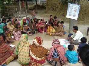 Health worker using a safety chart at a courtyard meeting